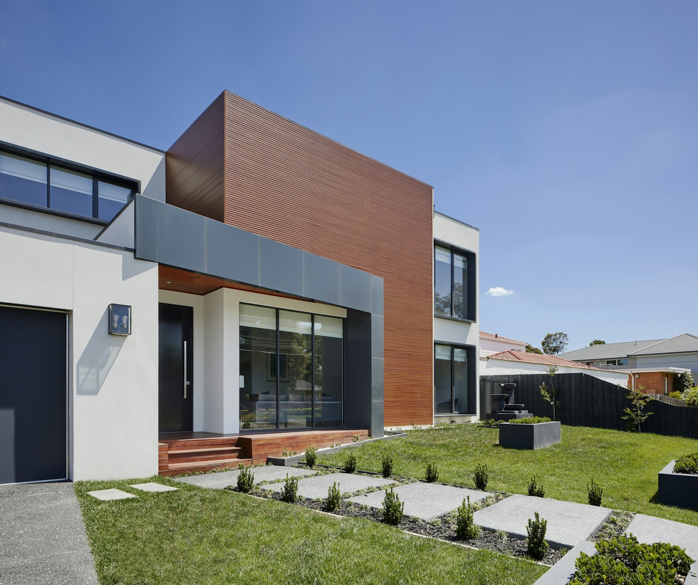 Paver walkway and stone entry steps leading to a modern front door
